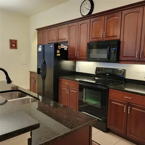 a kitchen with granite countertop a refrigerator stove and sink