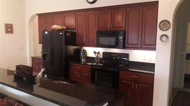 a kitchen with granite countertop wooden cabinets and black appliances