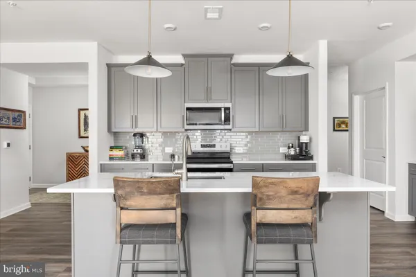 a kitchen with stainless steel appliances granite countertop a stove top oven a refrigerator a sink and a dining table with wooden floor