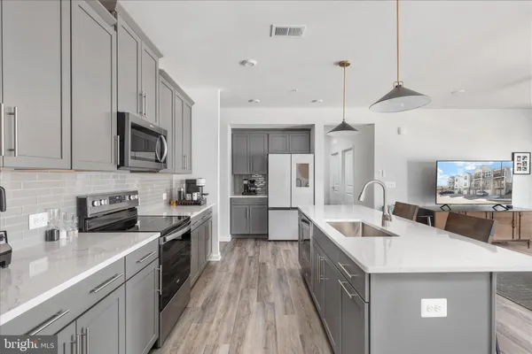 a kitchen with granite countertop a sink a counter top space stainless steel appliances and cabinets