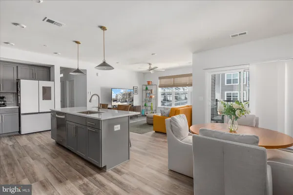 a kitchen with stainless steel appliances granite countertop a refrigerator a sink dishwasher a oven and a dining table with wooden floor