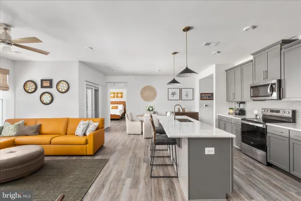 a living room with furniture kitchen view and a wooden floor