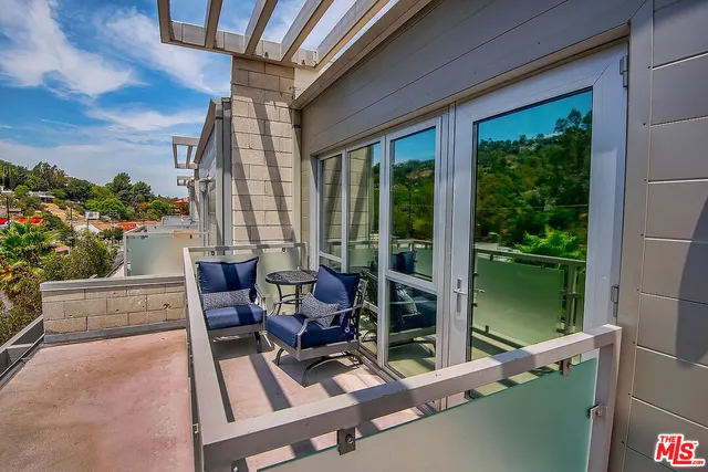 a living room with patio furniture and floor to ceiling windows
