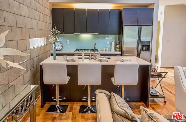 a kitchen with a stove a refrigerator and a table with wooden floor