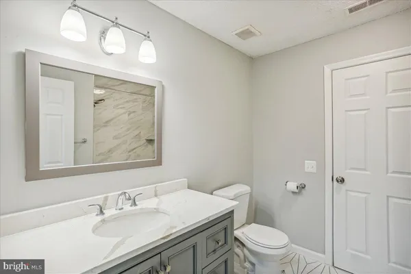 a bathroom with a sink vanity mirror and toilet