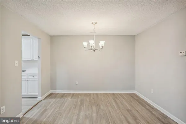 a view of an empty room with chandelier fan and wooden floor