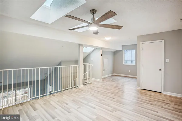 an empty room with wooden floor fan and windows
