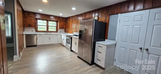 a kitchen with stainless steel appliances granite countertop a refrigerator a sink and white cabinets