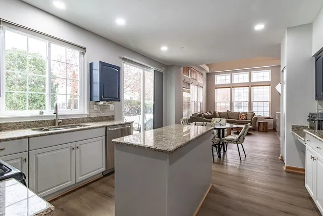 a very nice looking kitchen with granite countertop a stove a sink a dining table and chairs with wooden floor