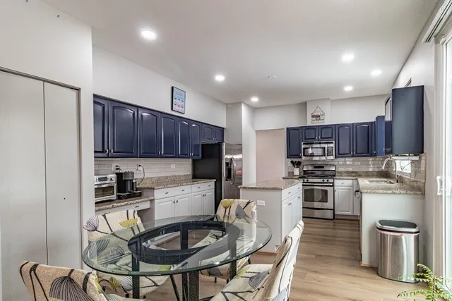 a kitchen with stainless steel appliances granite countertop a stove top oven a refrigerator a sink and chairs