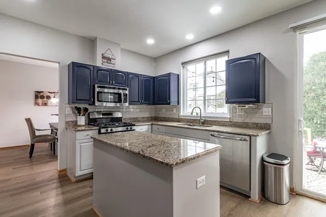 a kitchen with stainless steel appliances granite countertop a stove a sink dishwasher a microwave oven and a refrigerator with wooden floor