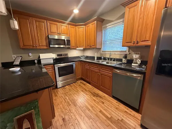 a kitchen with stainless steel appliances granite countertop wooden cabinets a stove top oven a sink and dishwasher