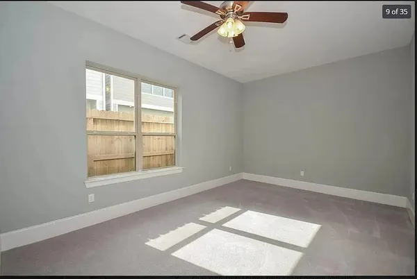 an empty room with a window and a fan