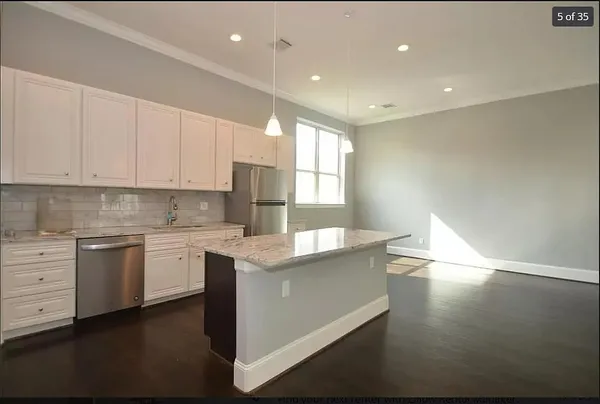 a large kitchen with granite countertop a white stove top oven and white cabinets