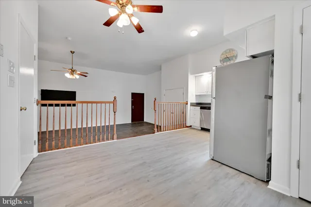an empty room with wooden floor and ceiling fan