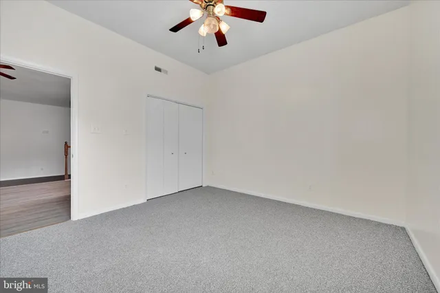 wooden floor in an empty room with a chandelier fan