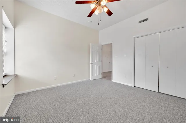 an empty room with a ceiling fan and a window