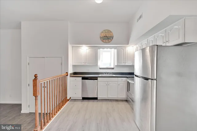 a kitchen with granite countertop a refrigerator and a stove top oven