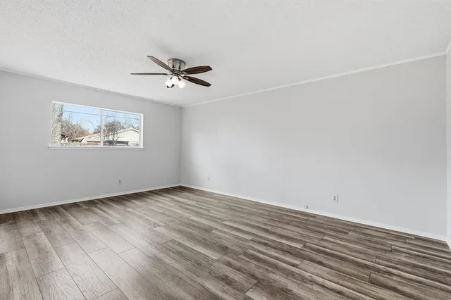 an empty room with wooden floor ceiling fan and windows