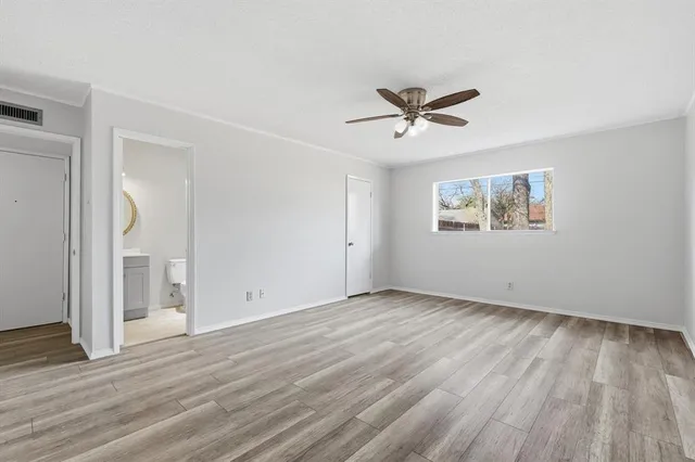 an empty room with wooden floor ceiling fan and windows