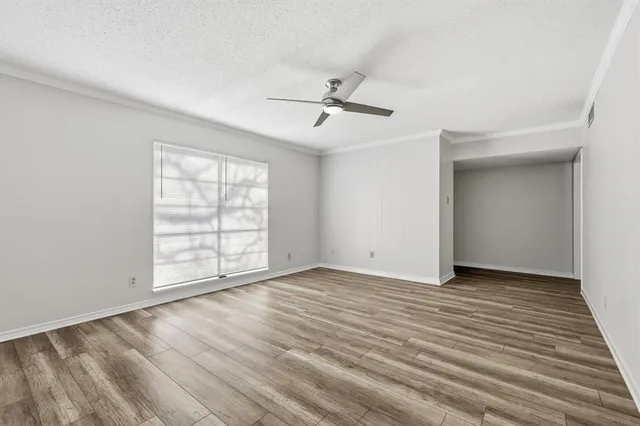 an empty room with wooden floor chandelier fan and windows