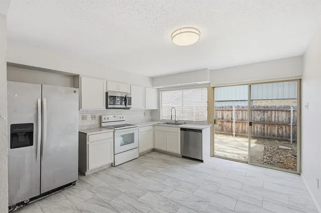 a kitchen with white cabinets and refrigerator