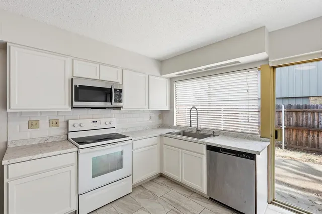 a kitchen with stainless steel appliances white cabinets and white appliances