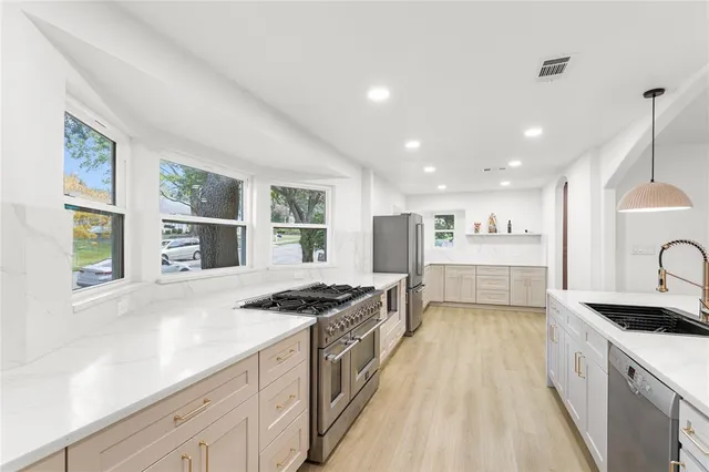 a kitchen with stainless steel appliances granite countertop a stove a sink and a refrigerator