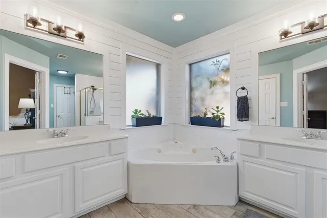 a bathroom with a bathtub a double vanity sink and mirror