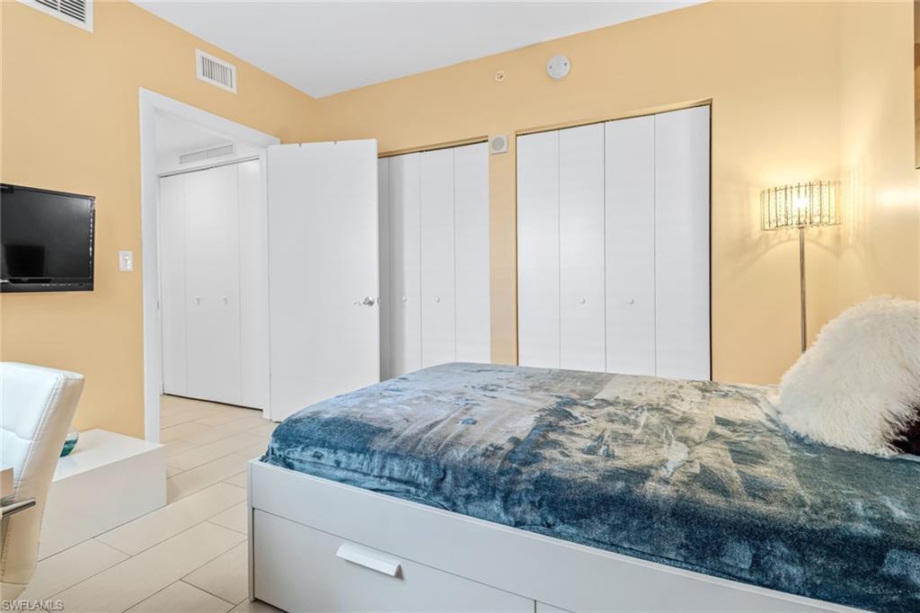 3000 Oasis Grand Boulevard, Unit 2205 Fort Myers, FL 33916 - Photo 21 of 42 a bedroom with a large bed and a flat screen tv