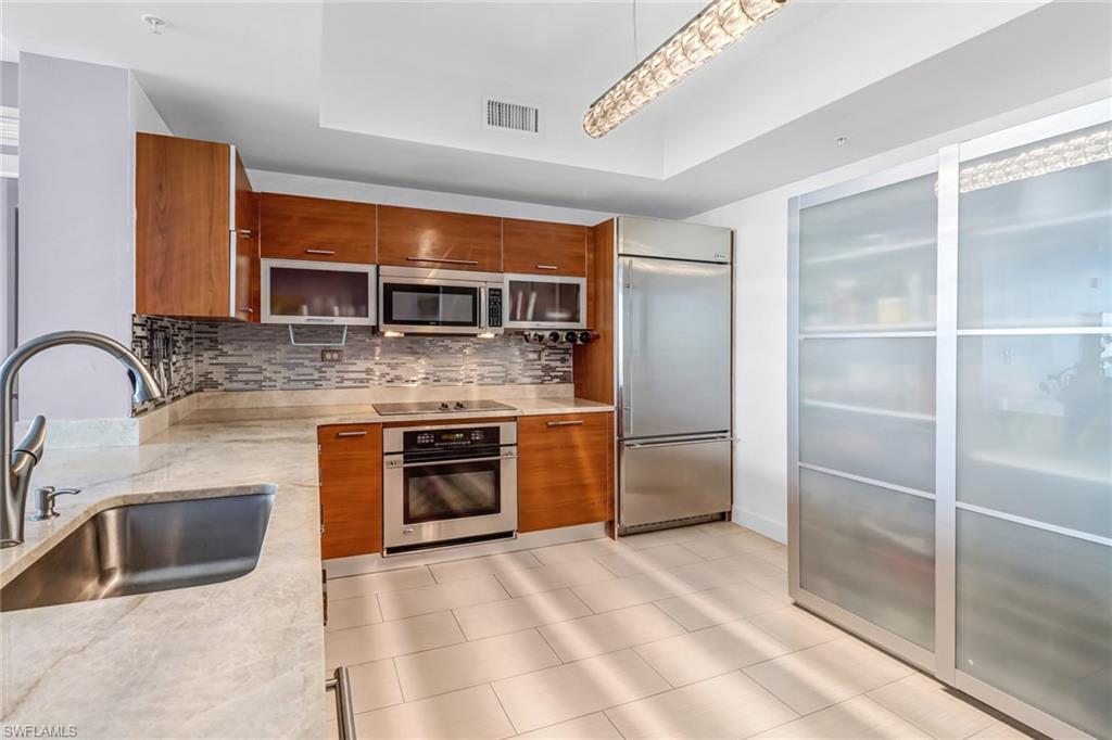 3000 Oasis Grand Boulevard, Unit 2205 Fort Myers, FL 33916 - Photo 8 of 42 a kitchen with stainless steel appliances granite countertop a sink stove and refrigerator
