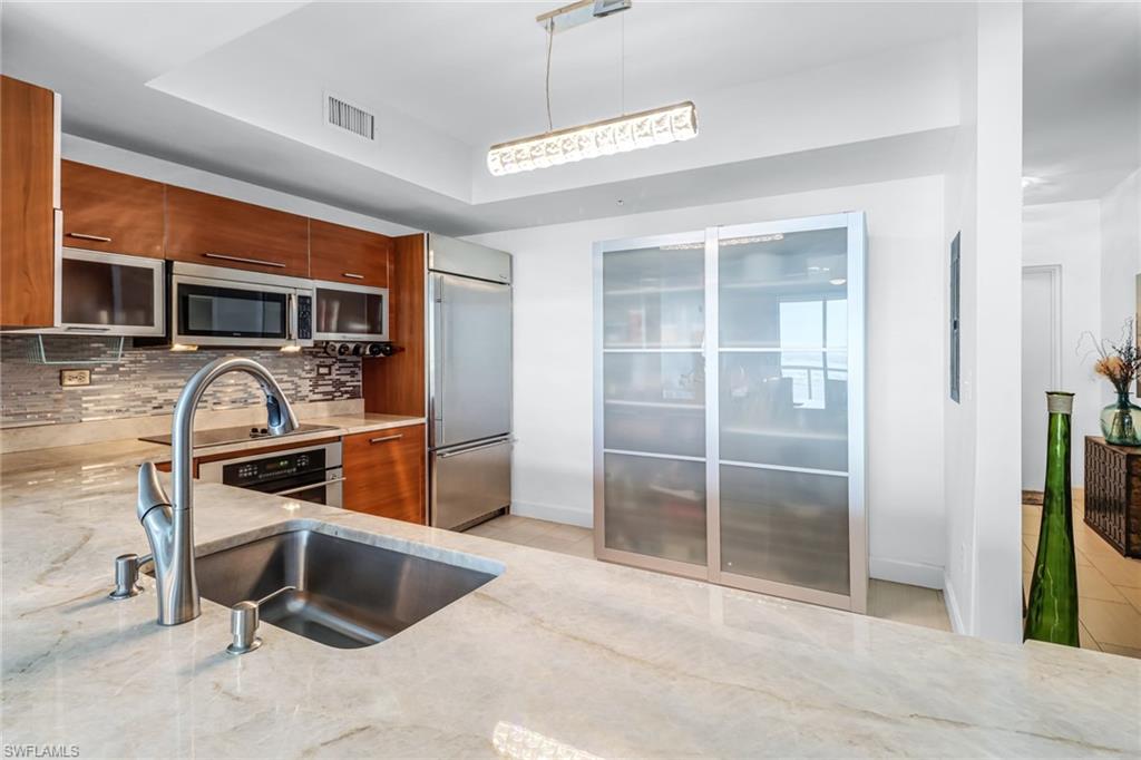 3000 Oasis Grand Boulevard, Unit 2205 Fort Myers, FL 33916 - Photo 9 of 42 a kitchen with stainless steel appliances granite countertop a refrigerator and a sink