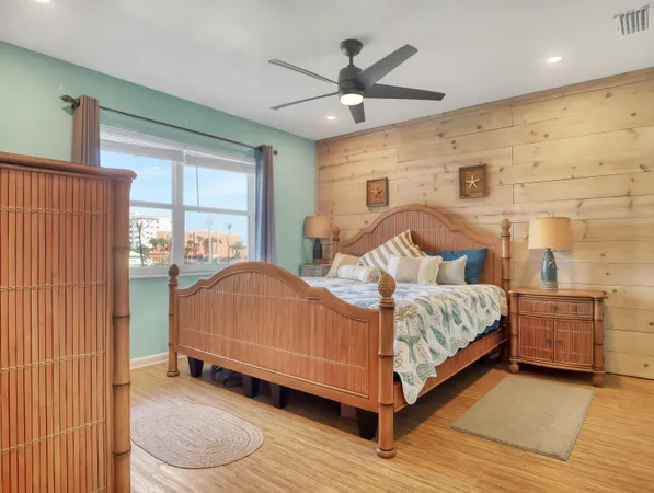 a bedroom with a bed and dresser with wooden floor