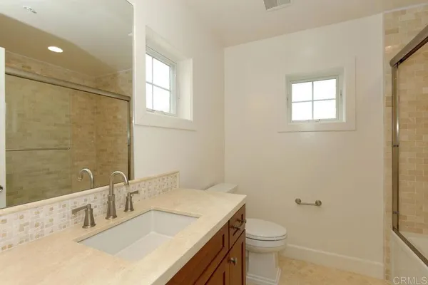 a bathroom with a granite countertop sink toilet and a mirror