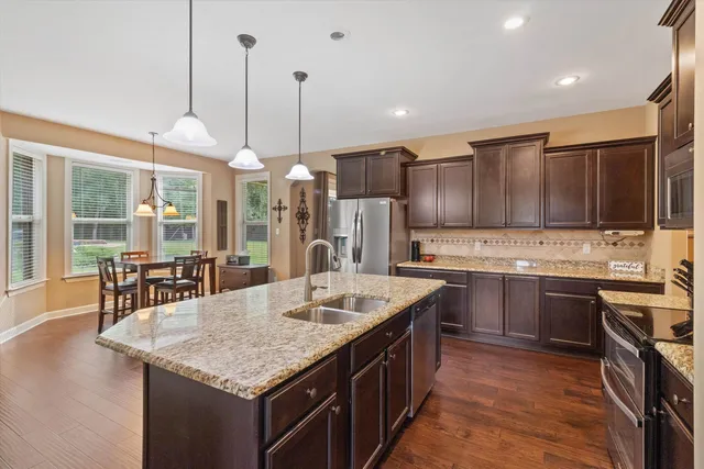 a kitchen with stainless steel appliances granite countertop a sink a stove and a wooden floors