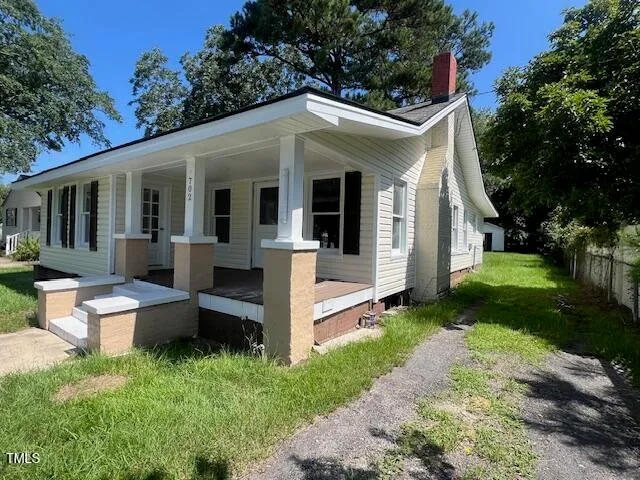 a view of a house with a yard and large tree