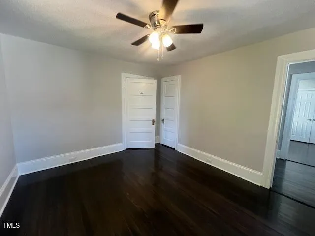 an empty room with wooden floor and fan