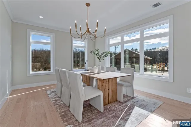 a dining room with wooden floor a chandelier a wooden table and chairs