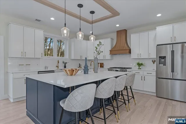 a kitchen with stainless steel appliances granite countertop a sink a stove a refrigerator and island with wooden floor