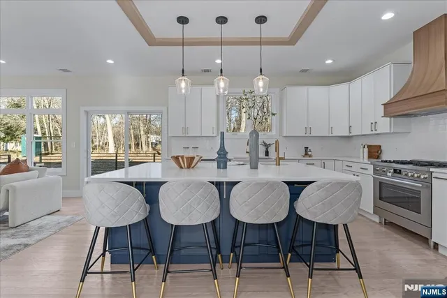 a kitchen with stainless steel appliances granite countertop a table chairs stove and white cabinets