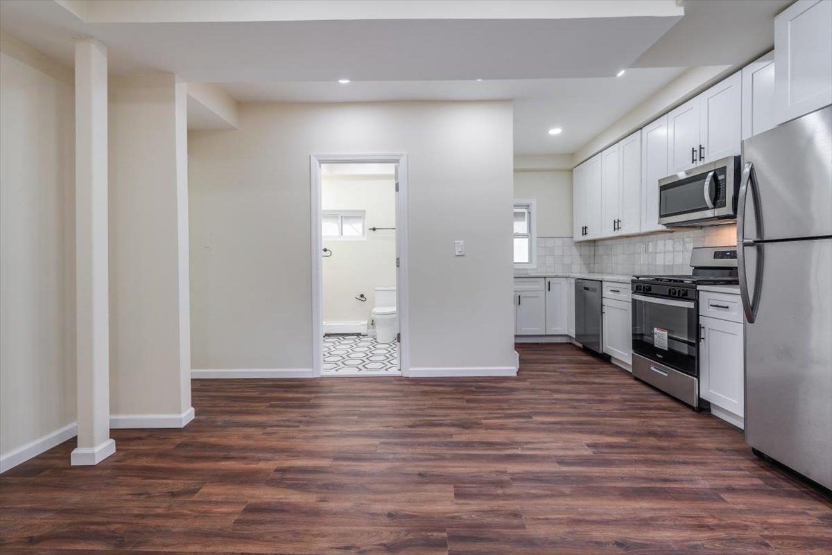 a view of kitchen view wooden floor and stainless steel appliances