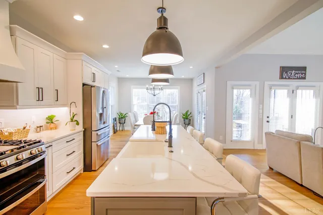 a large kitchen with stainless steel appliances a stove a refrigerator a sink dishwasher a dining table and chairs with wooden floor