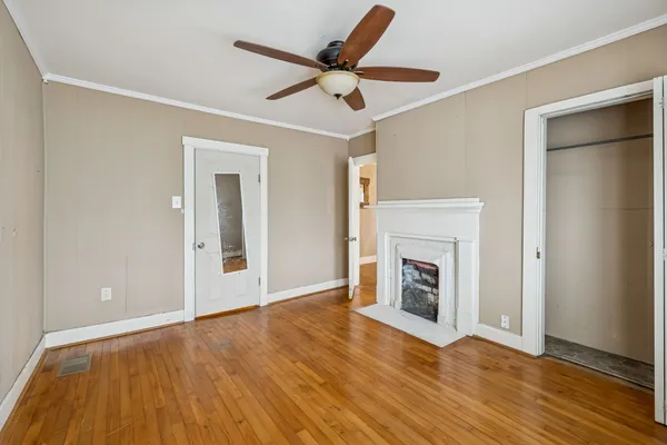 a view of an empty room with wooden floor fireplace and a window