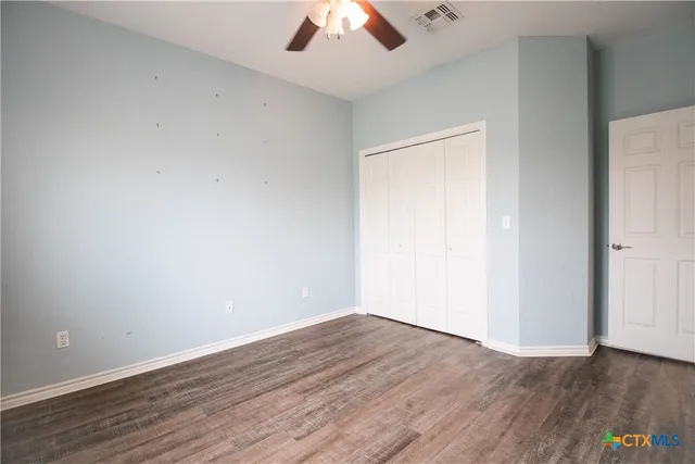 an empty room with wooden floor chandelier and windows