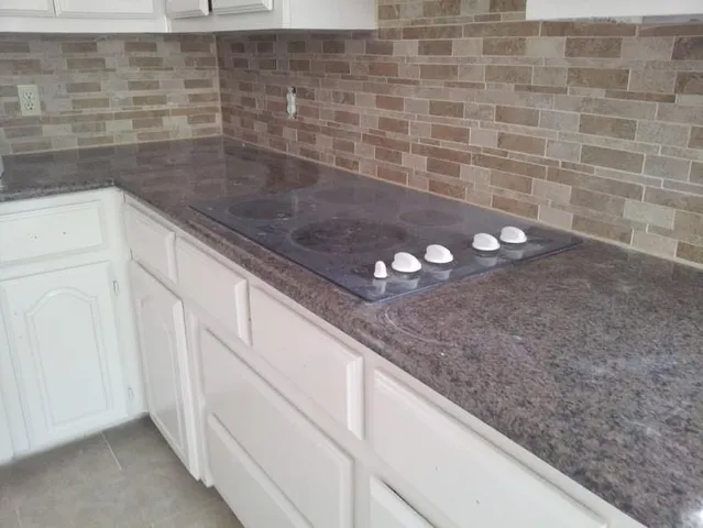a bathroom with a granite countertop sink and white cabinets
