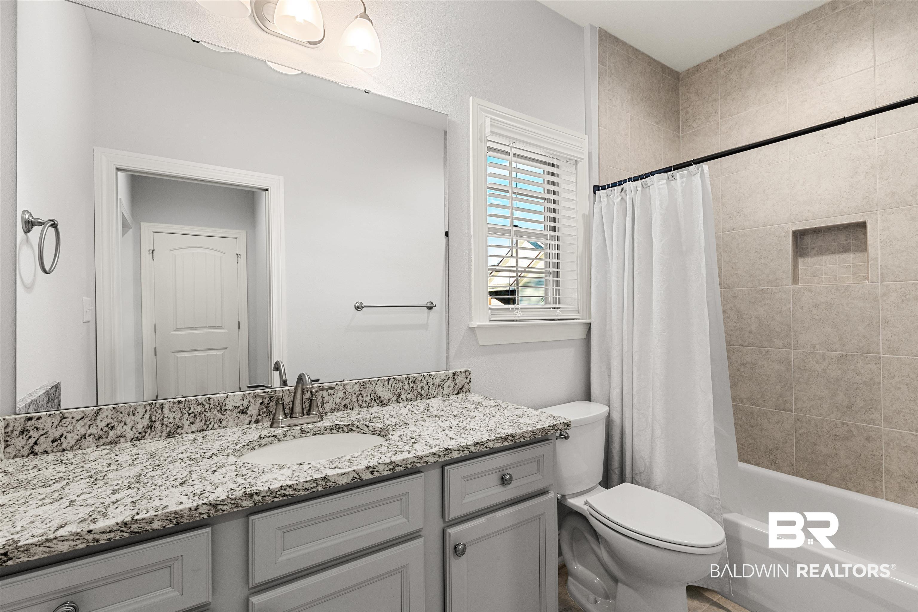 702 Holmes Avenue, Unit 702 Foley, AL 36535 - Photo 20 of 33 Full bathroom featuring shower / bathtub combination with curtain, vanity, and toilet