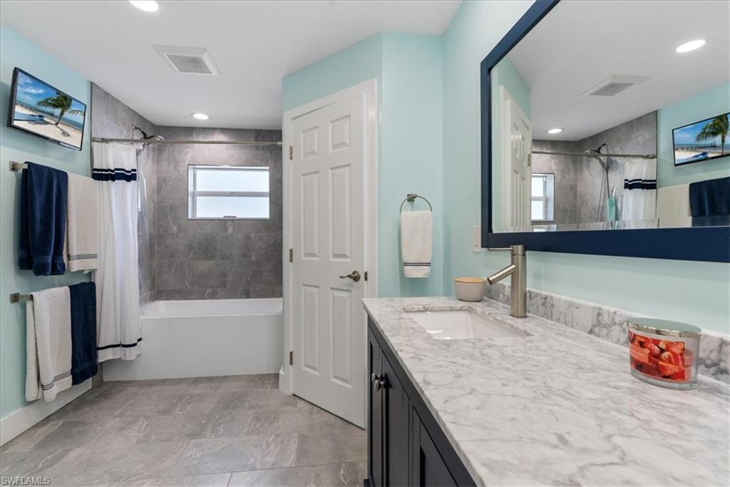1820 19th Street Southwest Naples, FL 34117 - Photo 14 of 31 a bathroom with a granite countertop sink a mirror a vanity and bathtub