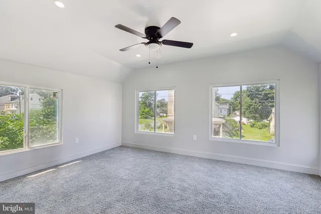 en empty room with a ceiling fan and carpet