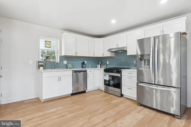 a kitchen with granite countertop white cabinets and stainless steel appliances