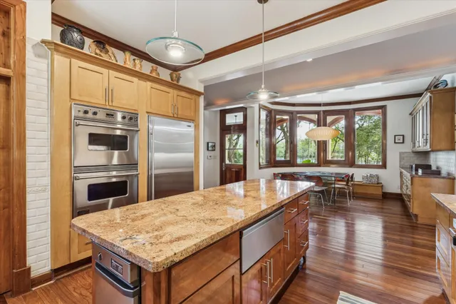 a kitchen with a center island wooden floor and stainless steel appliances